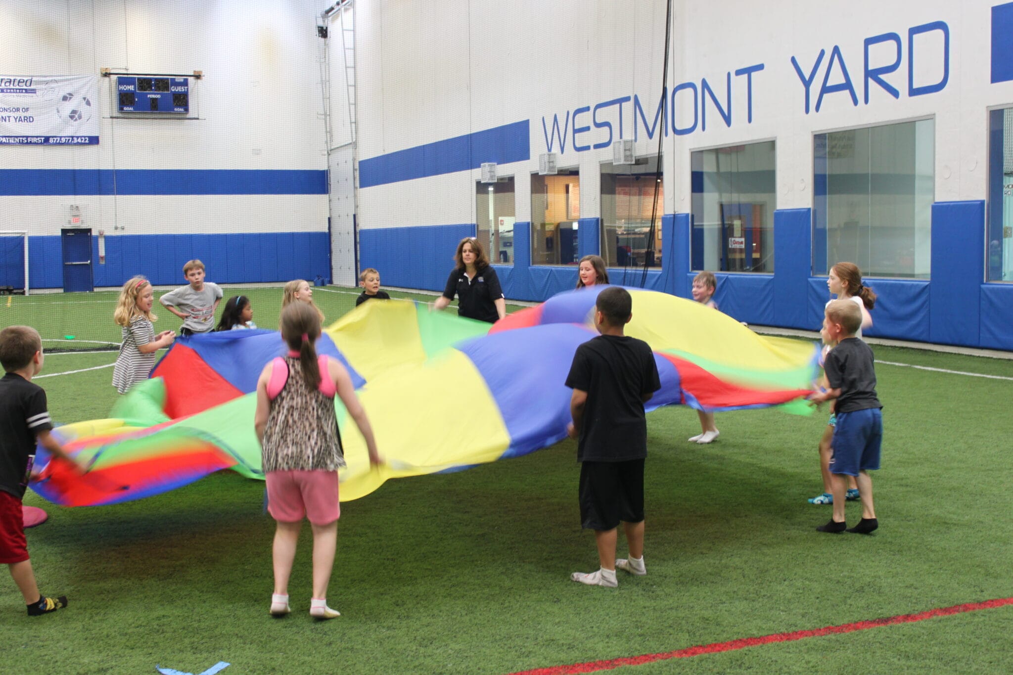 Children playing with a parachute on an indoor turf field at Milwaukee Yard Oak Creek WI