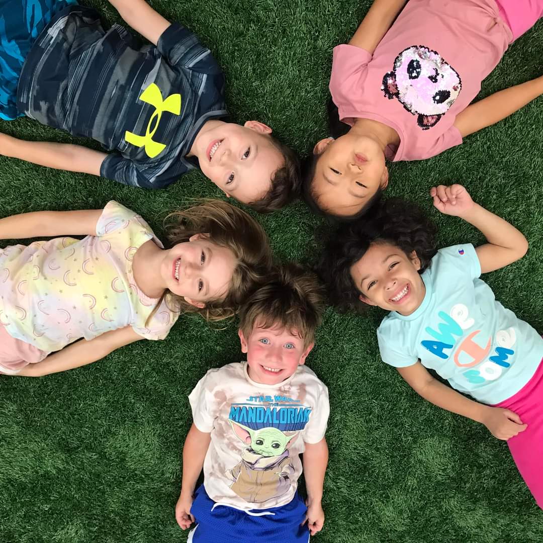 FUN Camp children laying on an indoor turf field at Milwaukee Yard Oak Creek WI