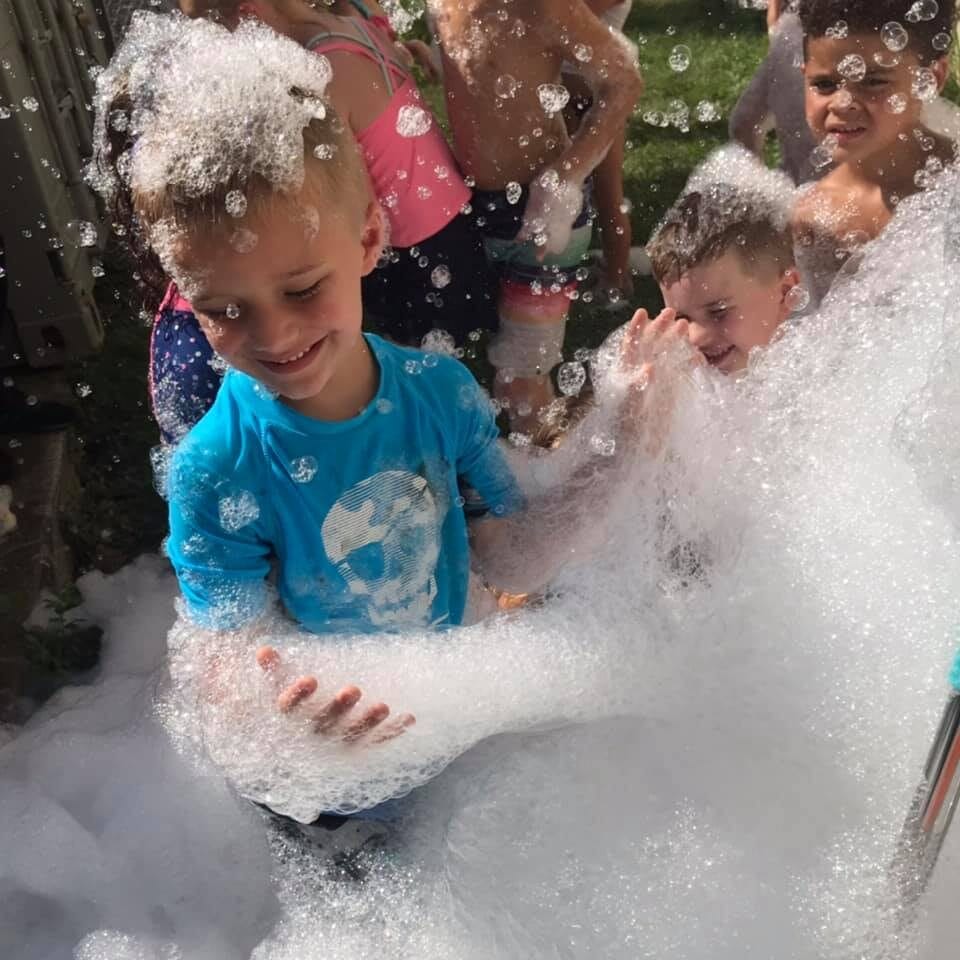 Child playing with bubbles outside with summer FUN camps Milwaukee Yard Oak Creek WI
