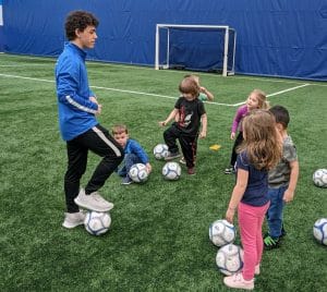 Mighty Tykes soccer coach leading toddlers through drills on indoor turf at Milwaukee Yard Oak Creek WI