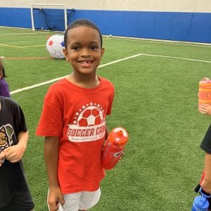 Young athlete smiling on indoor turf during youth training program at Milwaukee Yard partnered with Acceleration