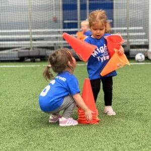 Two girls age 2 stacking cones at Mighty Tykes Milwaukee Yard Oak Creek WI
