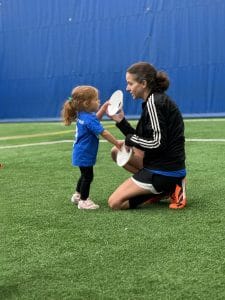 Parent participating on field with toddler during Mighty Tykes soccer class at Milwaukee Yard