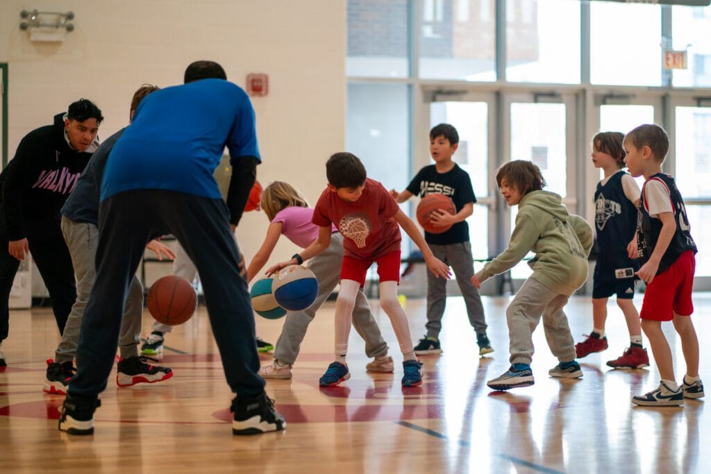 summer basketball camp, kids practicing dribbling with trained coach