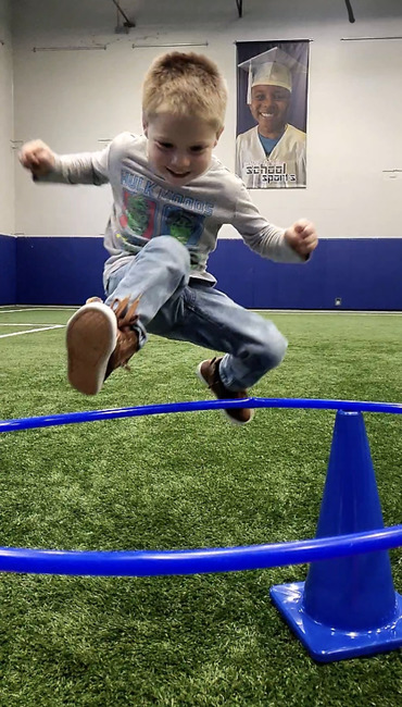 Preschool children running on indoor turf field during large motor play at Active Childcare Milwaukee Yard